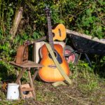 A photo of some props ready for our artists, an acoustic guitar, an old fashioned radio and a wheel barrow in the Down to Earth allotment.