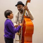 Photo of young audience members exploring a double bass with character Buddy in Rain Rain