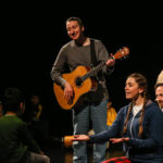 Photo of Bamboozle AS production Moon Song. Three performers introduce themselves to an audience member with live guitar music.