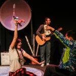 Photo of Bamboozle's AS production Moon Song. An actor and an audience member interact with rockets as they fly through space.