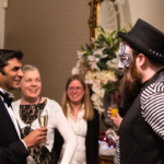 Photo of Gala guest enjoying a drink and talking to circus performer