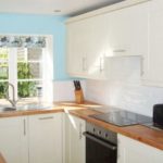Photo of pretty kitchen area with light blue wall