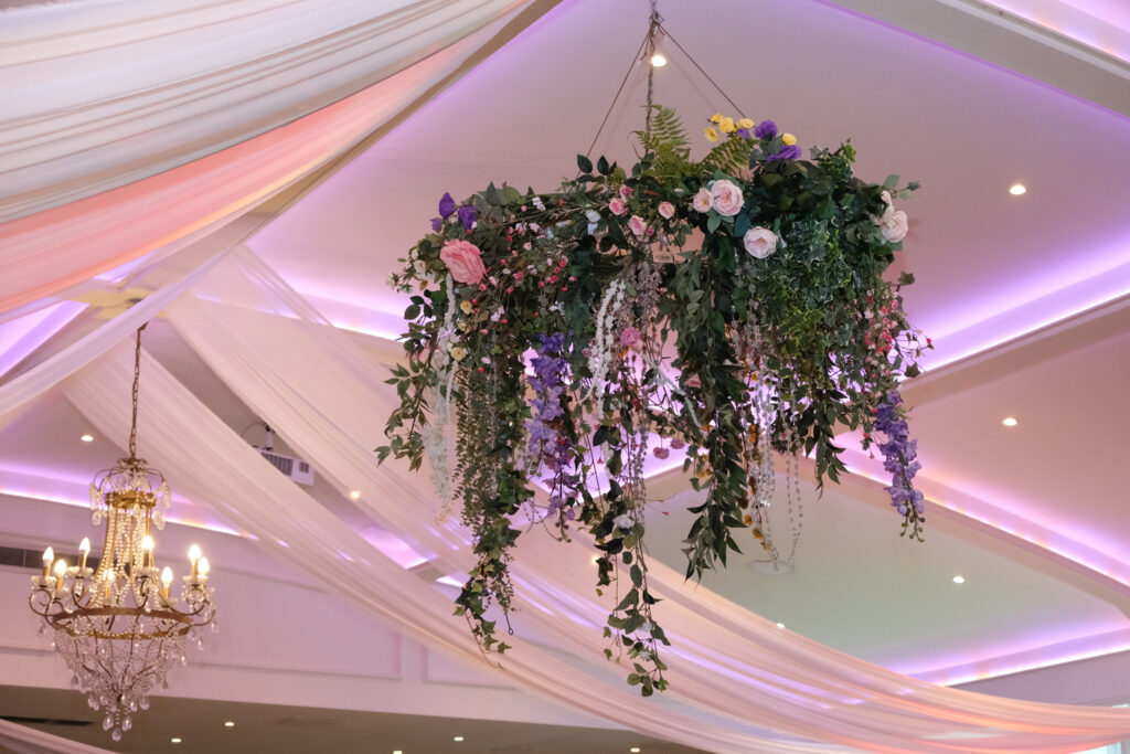 A hoop chandelier featuring trailing foliage and flowers in pinks, purples and whites.